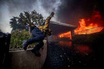 Un bombero salta sobre una valla en la zona de Palisades a 7 de enero de 2025.