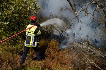 Un bombero usa una manguera para combatir un incendio forestal cerca de Le Luc, en el sur de Francia