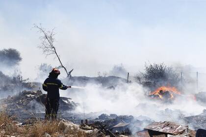Un bombero utiliza una manguera mientras intenta extinguir las llamas después de que estallara un incendio forestal en Kitsi, un suburbio del sur de Atenas, el 19 de junio de 2024.