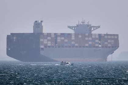 Un buque portacontenedores anclado mientras un pequeño bote de motor pasa frente a él en el estrecho de Ormuz frente a Bandar Abbas, Irán