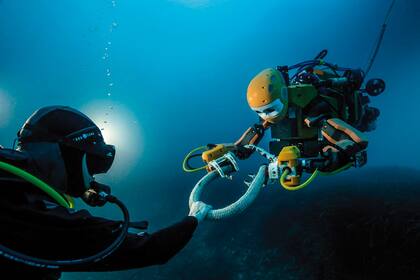 Un buzo interactúa con un arqueólogo submarino robótico