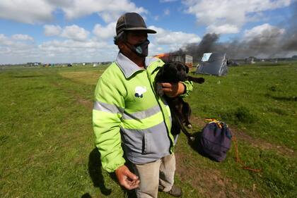 Un cachorro es llevado fuera del predio desalojado