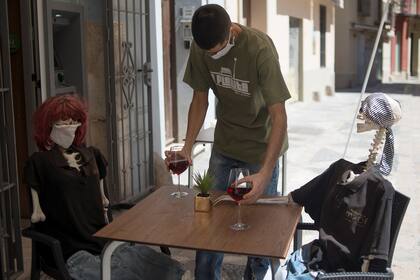 Un camarero sirve a esqueletos disfrazados de clientes en un bar en Málaga el 18 de mayo de 2020, en medio de la pandemia de coronavirus