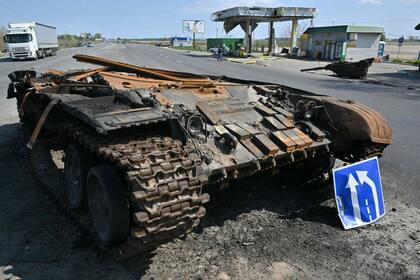 Un camión pasa por delante de los restos de un tanque ruso junto a una gasolinera destruida en el pueblo de Skybyn, en el noreste de la capital ucraniana, Kiev, el 2 de mayo de 2022.
