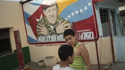 Un cartel pintado en la pared de una casa de Cienfuegos muestra a Hugo Chávez con las banderas de Cuba y Venezuela de fondo.