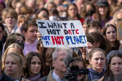Un cartel que dice en inglés "quiero una cita caliente. no un planeta caliente" se alza sobre la gente durante una manifestación de activistas contra el cambio climático en Berlín, viernes 23 de setiembre de 2022. 