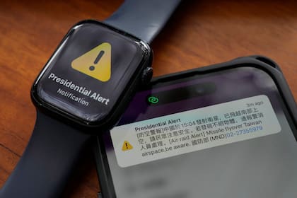 Un celular y un reloj con una alerta antiaérea en sus pantallas, juntos en una foto en Taipéi, Taiwán, el 9 de enero de 2024. (AP Foto/Ng Han Guan)