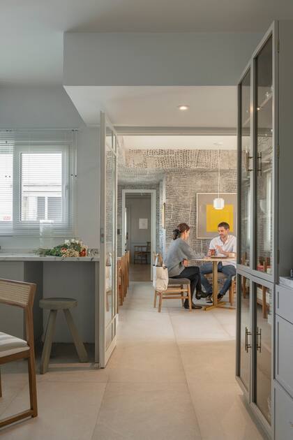 Un cerramiento con puertas de vidrio repartido separa la cocina del playroom.