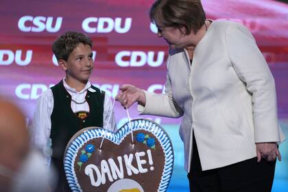 Un chico bávaro le entrega un regalo de agradecimiento a la canciller Angela Merkel por su gestión de gobierno