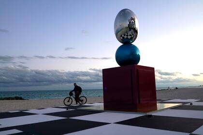 Un ciclista pasa junto a una instalación de arte titulada "Salón de las Visiones", de la artista Pilar Zeta de Argentina, en la playa del Hotel Faena durante la Semana del Arte de Miami.