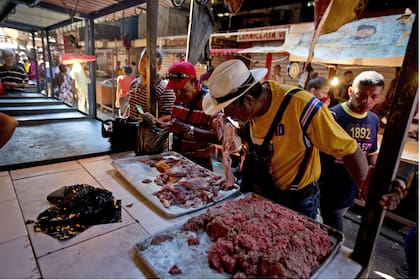 Un cliente huele un pedazo de carne en el mercado de Maracaibo