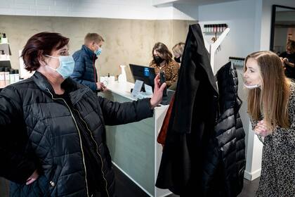 Un cliente muestra su teléfono móvil con un resultado negativo de la prueba de coronavirus Covid-19 a un peluquero en Koege, Dinamarca