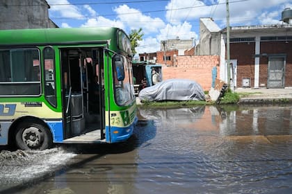 Un colectivo circula con dificultad por una calle anegada en Villa Caraza, Lanús, tras el intenso temporal