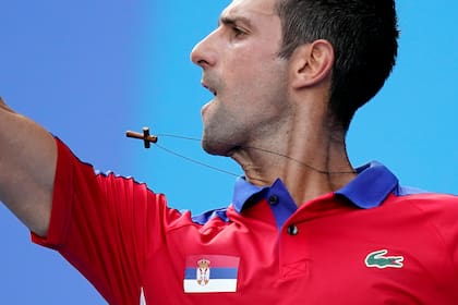 Un collar cuelga del cuello de Novak Djokovic cuando regresa a Hugo Dellien, de Bolivia, durante la competencia de tenis en los Juegos Olímpicos de Verano de 2020, el sábado 24 de julio de 2021 en Tokio, Japón.