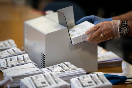 Un colportor usa guantes mientras procesa las boletas por correo en un almacén en la sede de la Junta Electoral del Condado de Anne Arundel el 7 de octubre de 2020 en Glen Burnie, Maryland