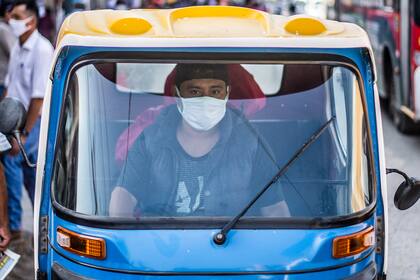 Un conductor de rickshaw con una máscara facial es visto afuera del mercado de Ciudad de Dios, en Lima el 11 de mayo de 2020, en medio de la nueva pandemia de coronavirus