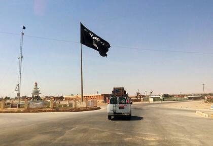 Un conductor pasa junto a una bandera del grupo Estado Islámico en el centro de Rawah, 281 kilómetros al noroeste de Bagdad, Irak (AP Foto/Archivo)