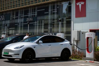Un conductor sube a su automóvil en una estación de carga de vehículos eléctricos fuera de un concesionario Tesla en Pekín, el sábado 24 de junio de 2023.