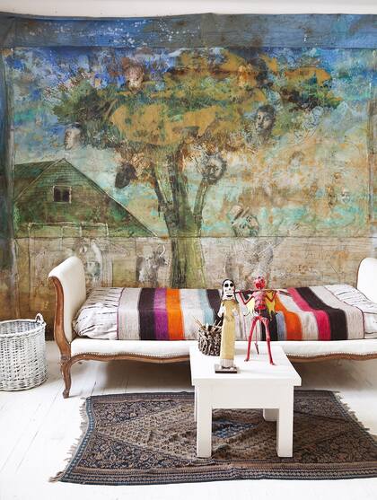 Un cuadro de su autoría es protagonista del cuarto de estar, donde ubicó una cama antigua con manta rústica multicolor