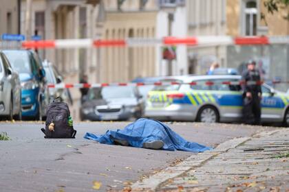 Un cuerpo tendido en la calle está cubierto mientras la policía bloquea el área alrededor del sitio de un tiroteo en Halle an der Saale, este de Alemania