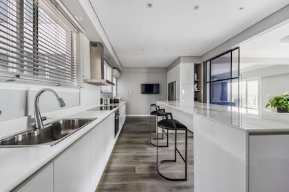 Un departamento sobre Avenida del Libertador con cocina integrada y la puerta de vidrio corrediza que permite separar o juntar cuando se desee