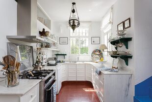 Un detalle maravilloso en esta cocina con un tradicional piso de baldosas color terracota: el enorme mueble curvo con tapa de mármol.