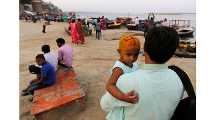 Un devoto hindú lleva a su hija después de una ceremonia religiosa a orillas del río Ganges en Varanasi