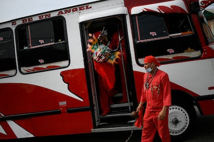 Un diablo bailarín, máscara en mano, sale de un autobús cuando llega para participar en las celebraciones del Corpus Christi en San Francisco de Yare, Venezuela