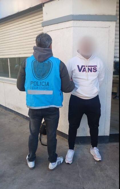 Un efectivo de la Policía de la Ciudad traslada a otro de los acusados, esposado y con ropa deportiva