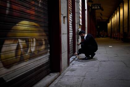 Un empleado cierra las persianas de un bar en Plaza Mayor, en Madrid