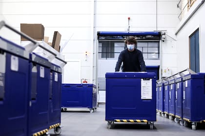 Un empleado de Cryonomic, una empresa belga que produce máquinas y contenedores de hielo seco que se utilizarán para el transporte de vacunas contra el coronavirus, empuja un contenedor de hielo seco médico en Gante el 2 de diciembre de 2020