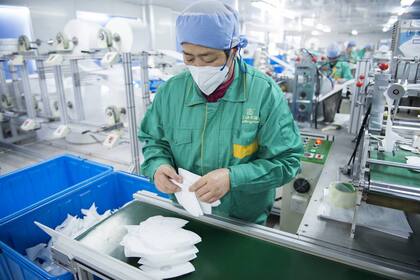 Un empleado de Dasheng revisa las mascarillas recién fabricadas