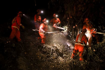 Un equipo de trabajo del Departamento de Correccionales de California trabaja en las líneas de contención para combatir el incendio Palisades el martes 14 de enero de 2025 en Santa Monica, California