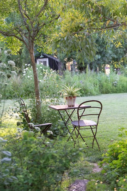 Un espacio de descanso bajo árboles convierte el jardín en un lugar para habitar y disfrutar