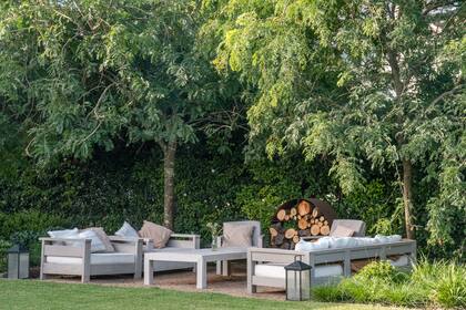 Un espacio de living exterior, dispuesto entre dos canteros laterales y mirando del frente al principal.