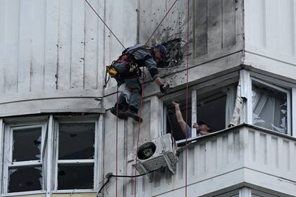 Un especialista inspecciona la fachada dañada de un edificio de apartamentos de varias plantas tras un ataque con drones en Moscú el 30 de mayo de 2023.