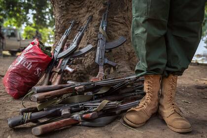 Un ex niño soldado se encuentra junto a los rifles entregados en la ceremonia de liberación