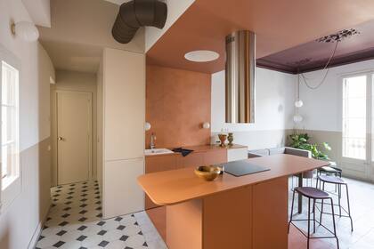 Un extractor cilíndrico en acero brillante (Electrolux) baja sobre el anafe. Otro círculo simétrico en la zona de trabajo aloja una luz creando el efecto de una lámpara de techo sin agregar elementos.