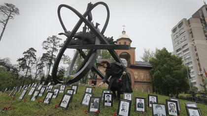 Un familiar coloca una ofrenda en el memorial de las víctimas en Kiev