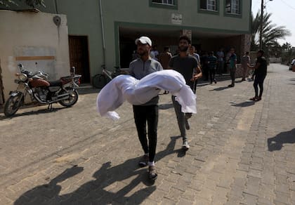 Un familiar lleva el cuerpo de la familia Abu Dagga, que murió en un ataque aéreo israelí, durante su funeral en Khan Younis, en el sur de la Franja de Gaza, el sábado 7 de octubre de 2023. (AP Photo/Yousef Masoud)