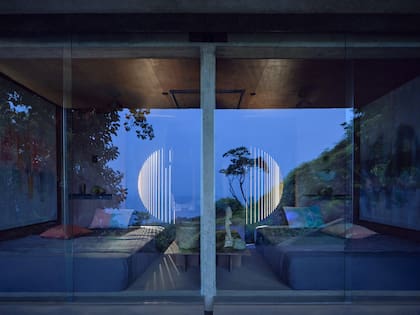 Un frente continuo de mobiliario con puertas de acero caladas a láser se transforma por la noche en un objeto luminoso, proyectando dibujos que evocan la luna y un cielo estrellado.