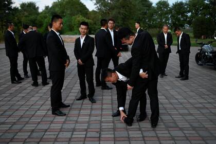 Un grupo de aprendices charlan después del entrenamiento en la entrada de la Academia de Seguridad Genghis en Tianjin