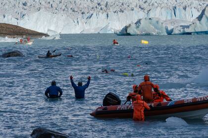 Un grupo de asistentes en la orilla del Lago Argentino ayudan a los corredores 
Gentileza: Nadando Argentina