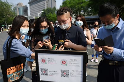 Un grupo de ciudadanos escanea su estado de salud a través de una aplicación de rastreo en Pekín