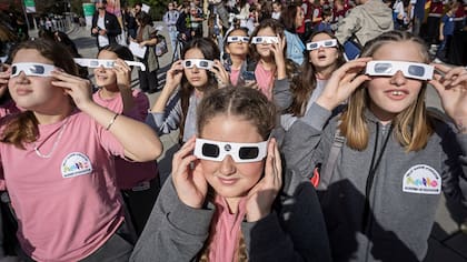 Un grupo de estudiantes se protegen la vista para ver el eclipse solar (AP Photo/Visar Kryeziu)