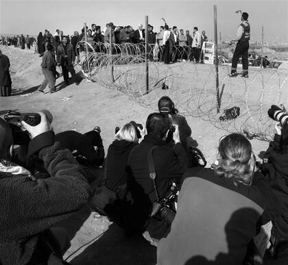 Un grupo de fotógrafios registra la reunión de familiares y amigos de detenidos en las puertas de la prisión de Abu Ghraib, en Bagdad, en 2004