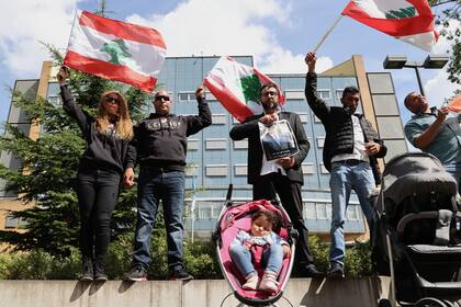 Un grupo de gente se reúne y agita banderas del Líbano frente al Tribunal Especial para el Líbano respaldado por la ONU en Leidschendam