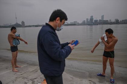 Un grupo de hombres junto al río Yangtze en Wuhan, la ciudad de China donde surgió el coronavirus por primera vez el año pasado