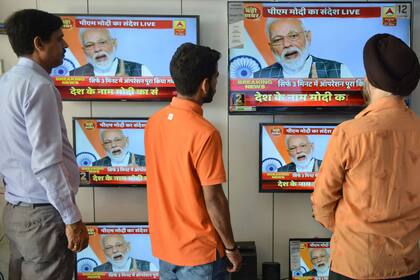 Un grupo de indios ve la transmisión en vivo del discurso del primer ministro Narendra Modi