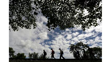 Un grupo de inmigrantes espera el paso del tren en Veracruz, luego de recibir alimentos en Las Patronas, para continuar su vieje